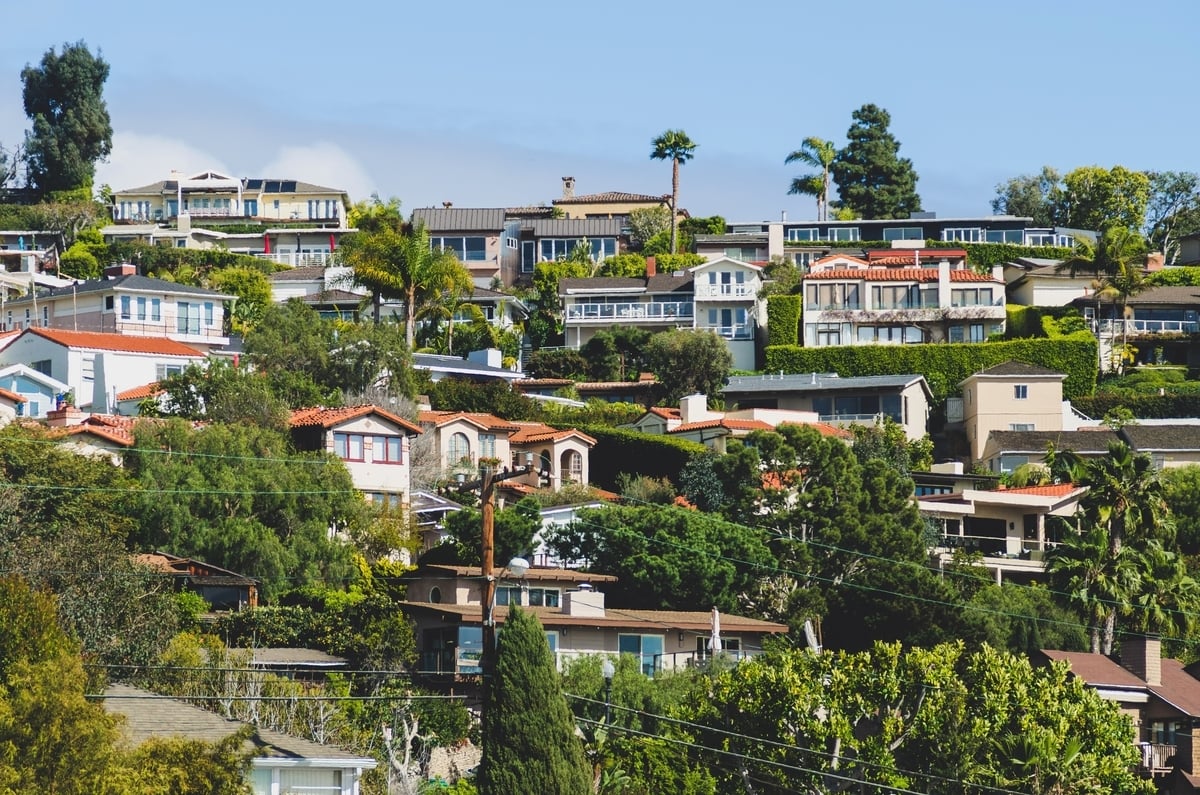 Expensive homes, houses, real estate perched on a hill with blue sky above