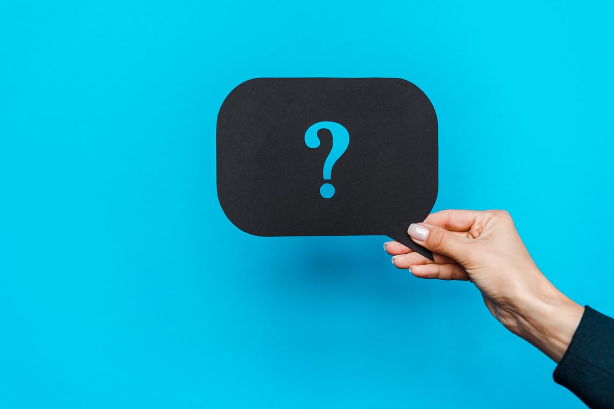woman holding black speech bubble with question mark on blue