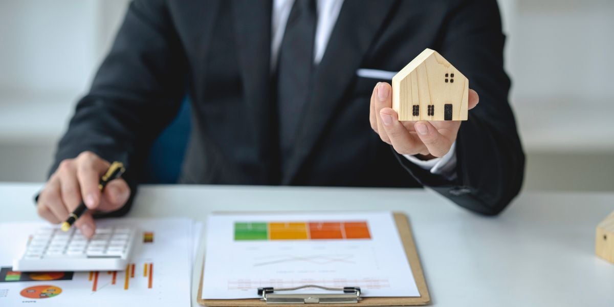 03 property manager holding house model and studying market trends 03 property manager holding house model and studying market trends