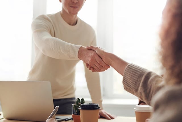People shaking hands over a desk People shaking hands over a desk